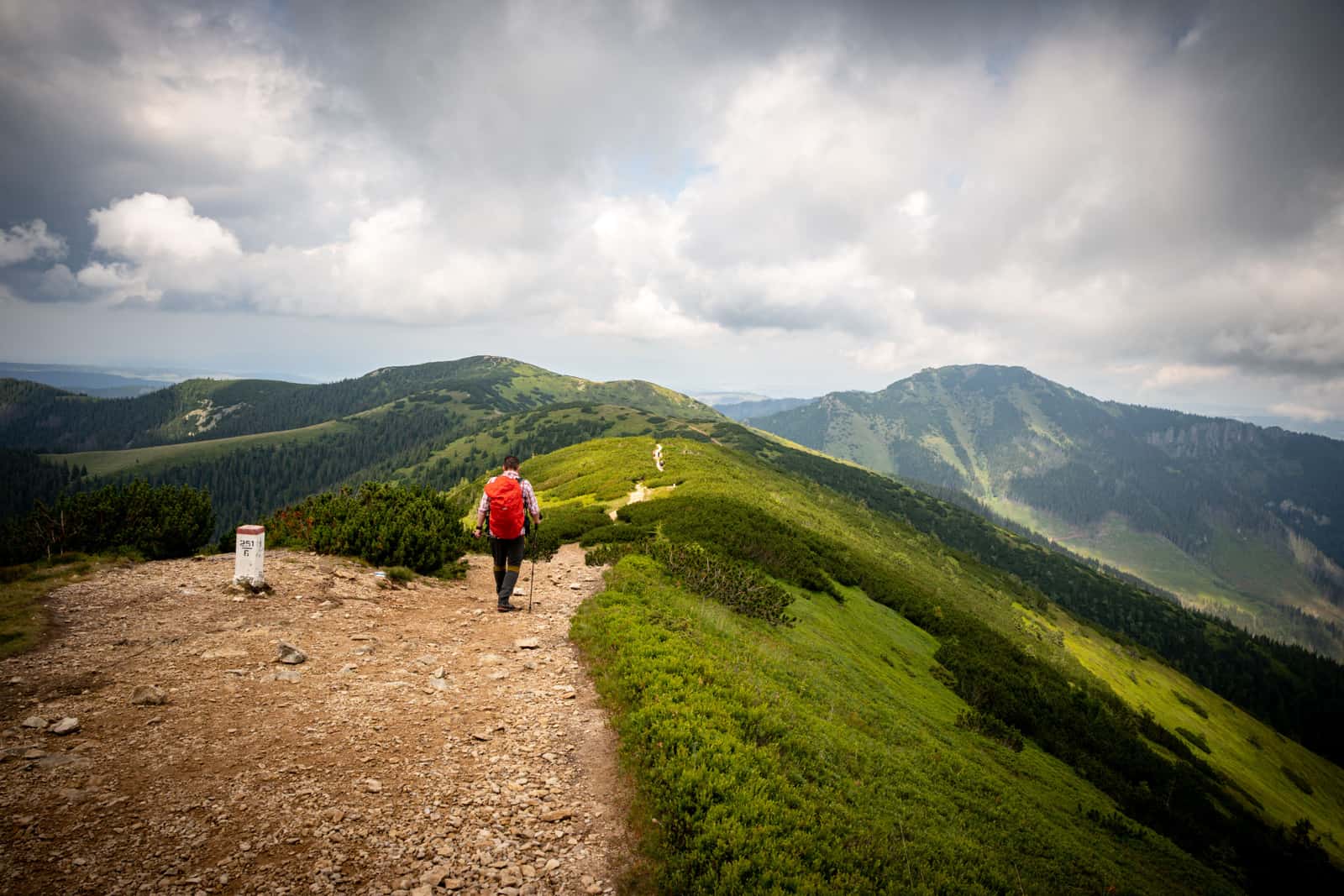 Illustrative stock photo: a hiker with a backpack on a mountain trail