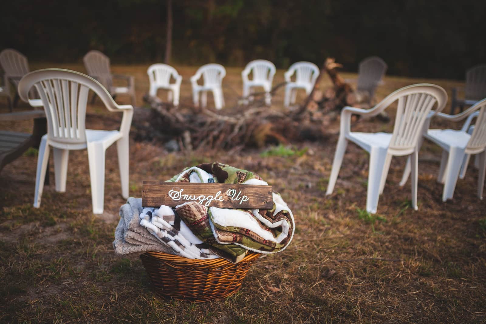 Camp chairs and blankets arranged around a campfire