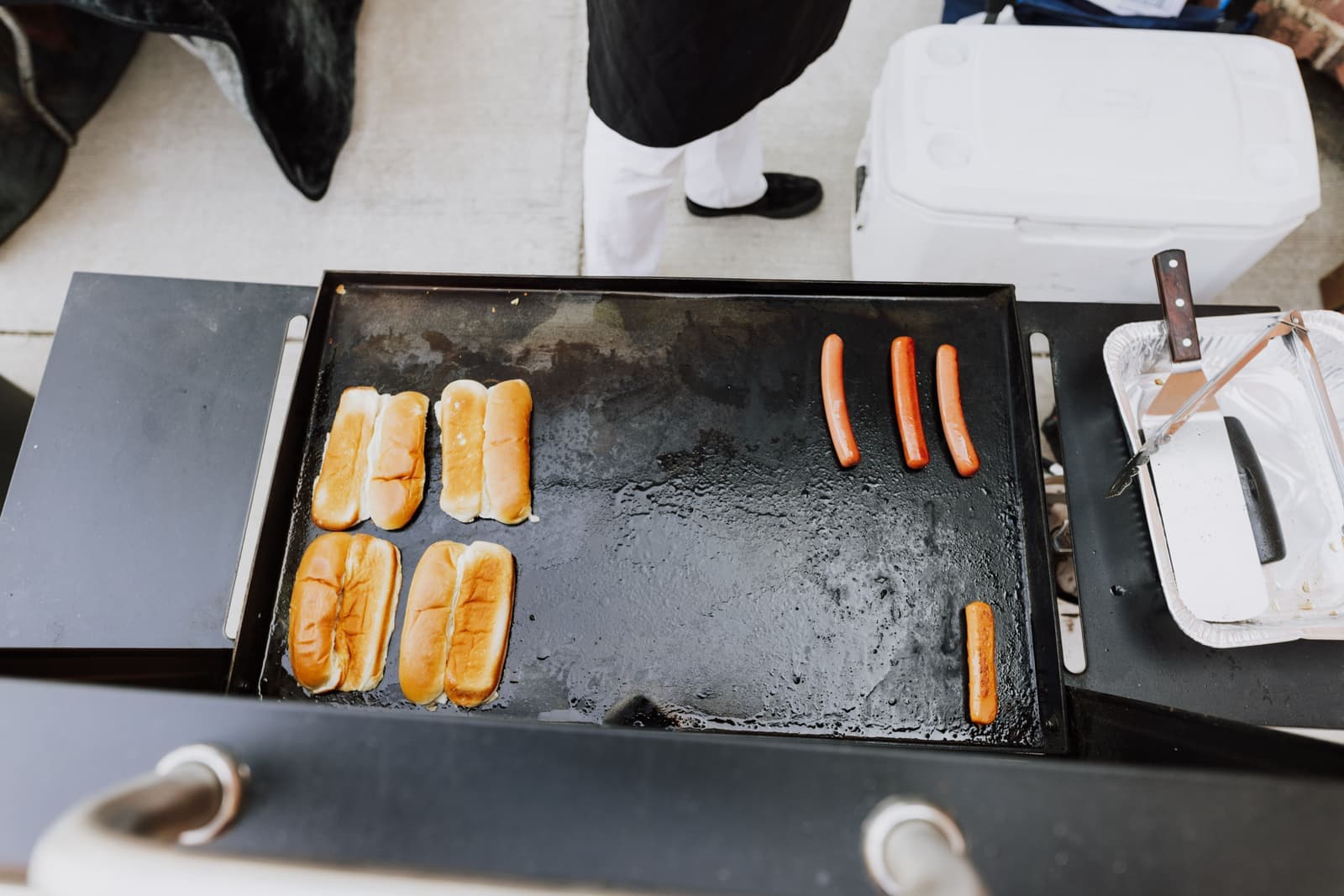 Hot dogs and buns grilling at an outdoor cookout