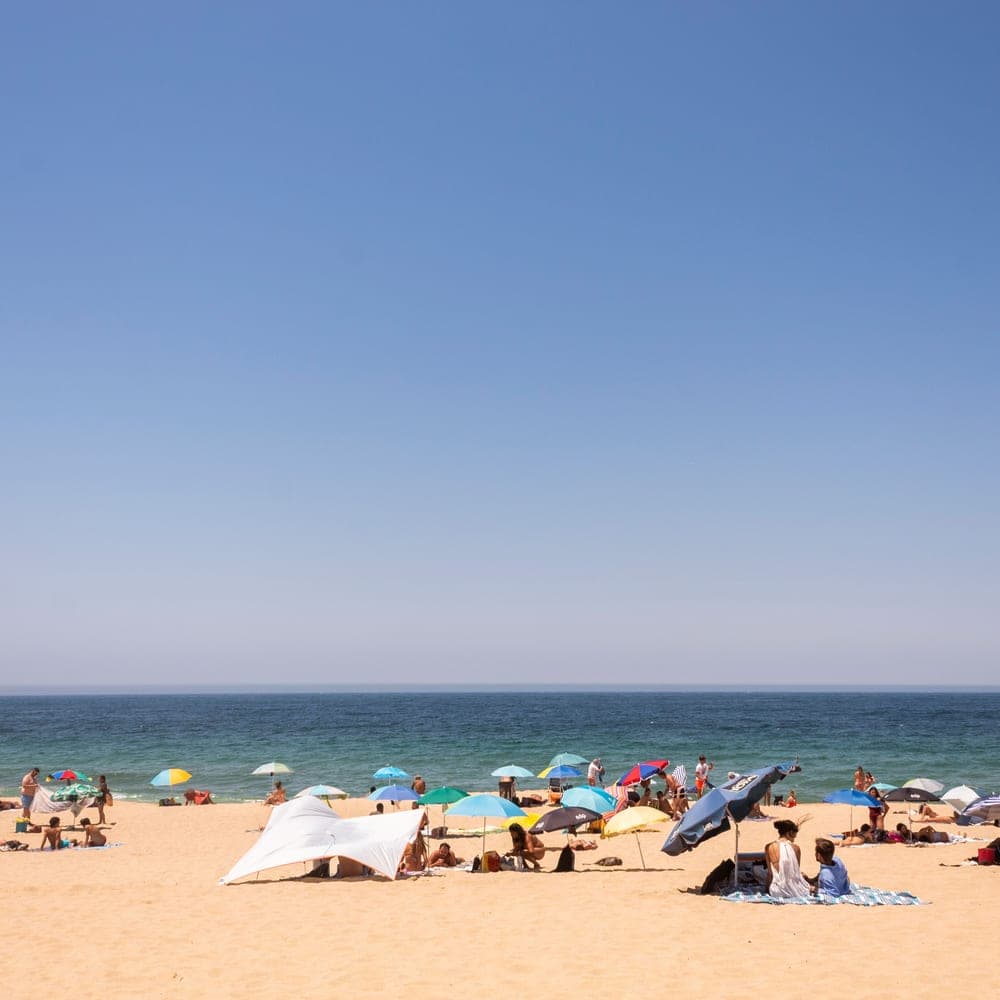 Illustrative stock photo: colorful umbrellas shading people on a sunny beach