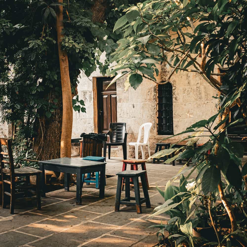 Illustrative stock photo: an outdoor patio with mixed chairs and a table under greenery