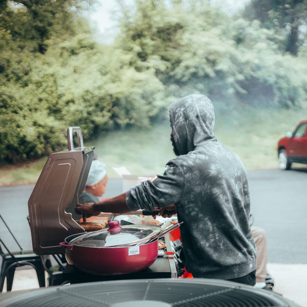 Illustrative stock photo: a man grilling food outdoors on a summer day