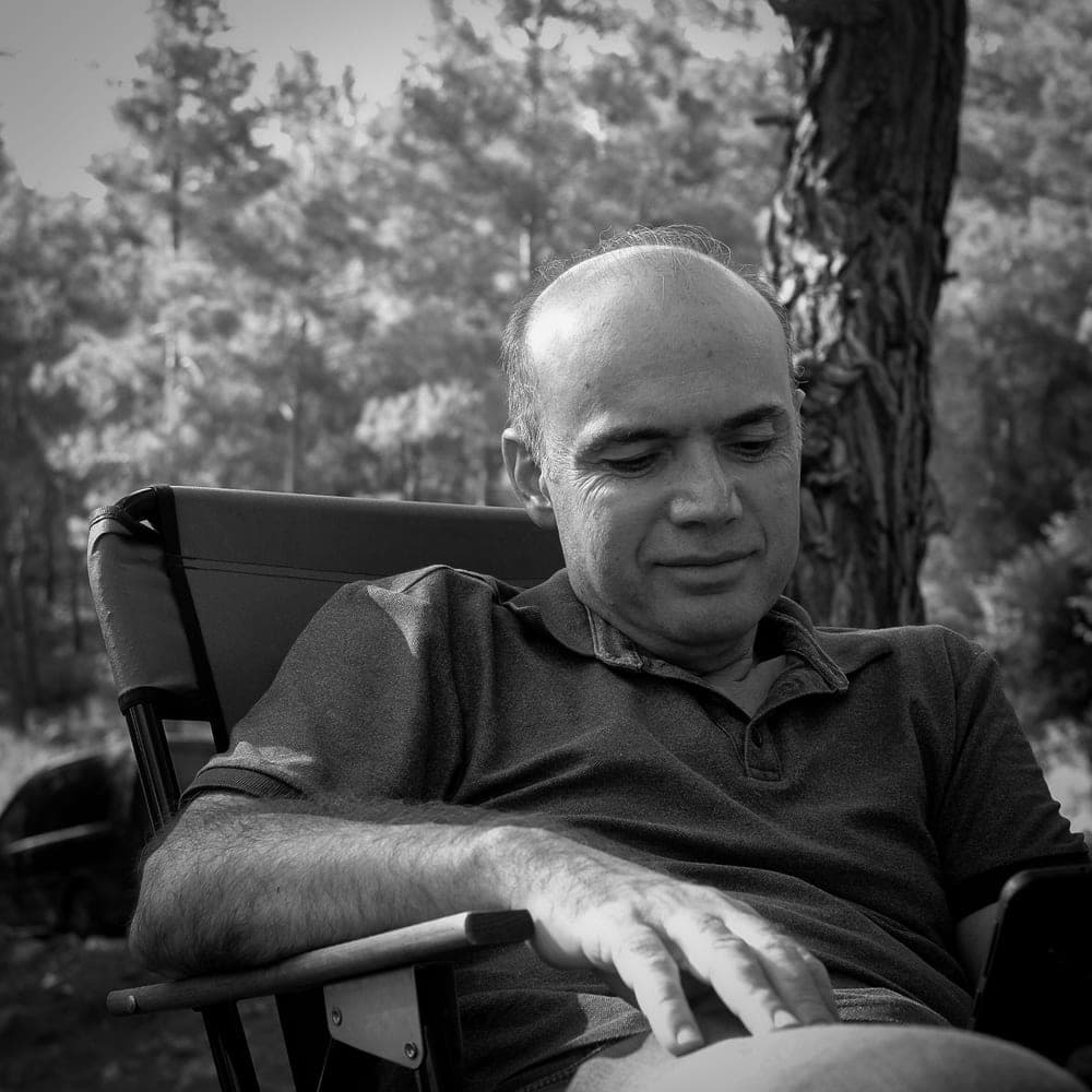 Illustrative stock photo: a man relaxing and reading in a forest campsite