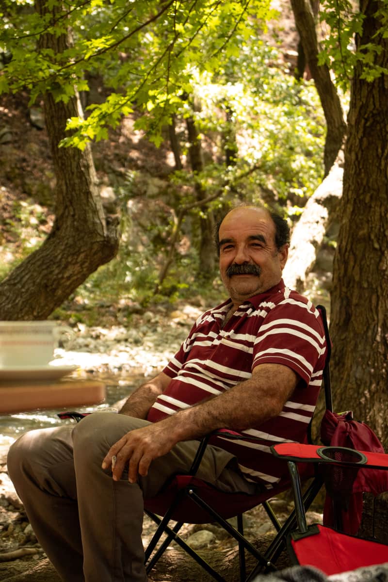 Illustrative stock photo: an older man sitting in a camping chair in a forest