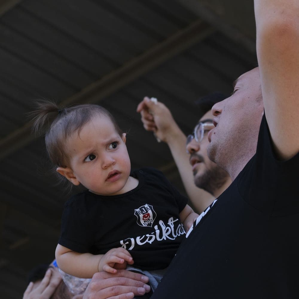 Illustrative stock photo: a young child with family at a sunny outdoor sports event