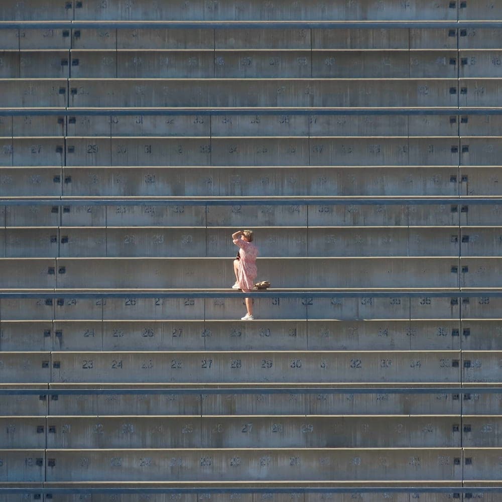 Illustrative stock photo: a person walking along empty stadium bleachers