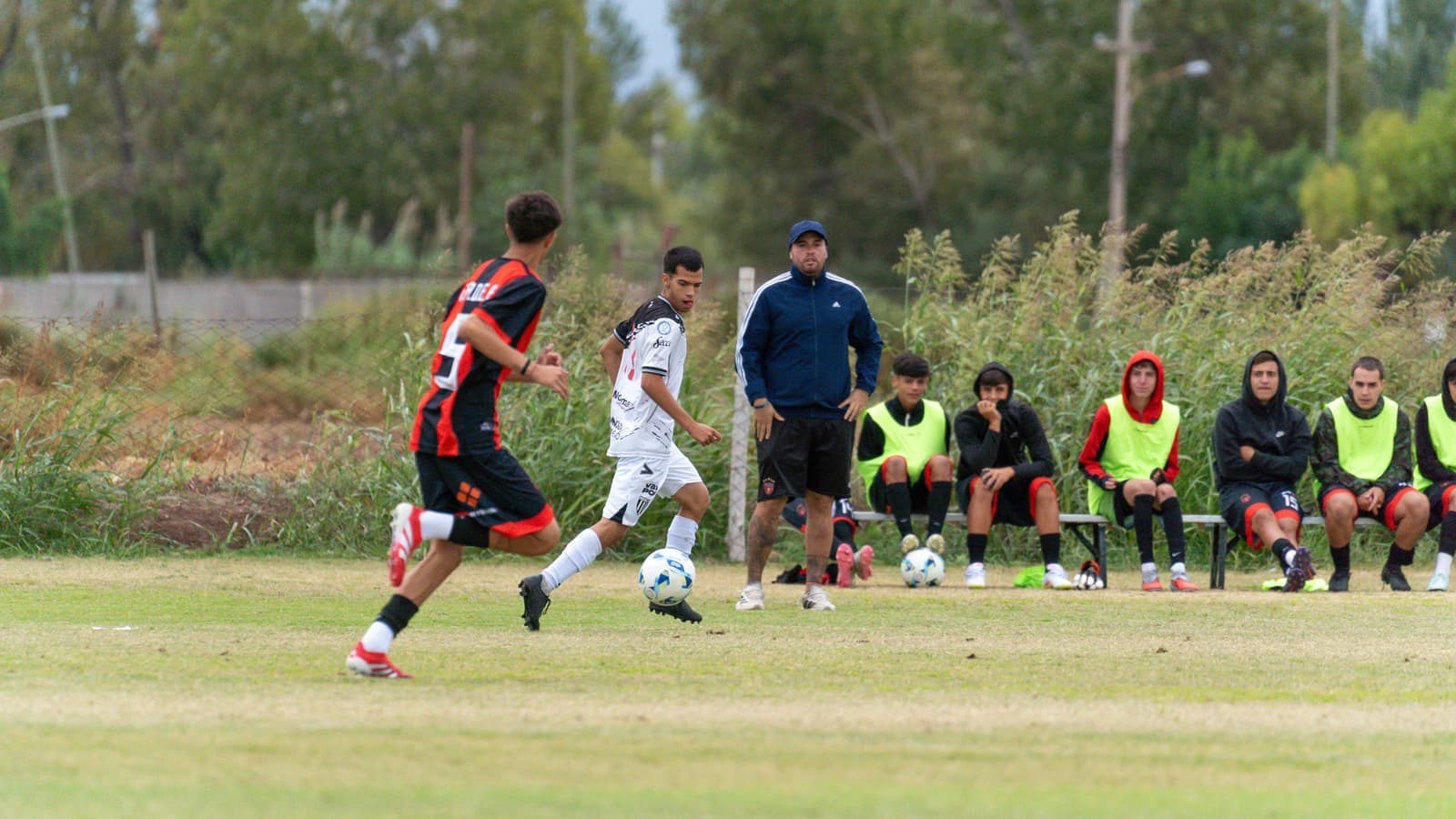 An amateur soccer match with a coach watching from the sideline